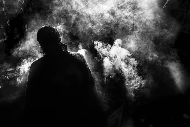 Foto branca e preta, com a silueta de um homem de costas envolto em fumaça. A foto ilustra o artigo Ritual de Limpeza: Como fazer o seu? do site Ori Mystyco