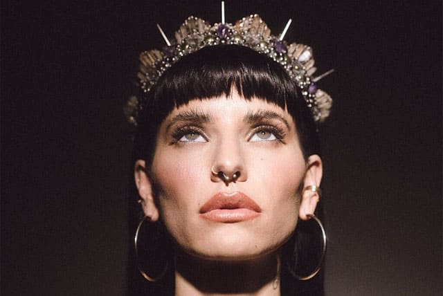 Foto de uma mulher de pele branc, com olhos verdes e boca rosada olhando para cima. O cabelo da mulher é castanho escuro e ela está com um coroa na cabeça. Ela simboliza a deusa Lilith ou Lilit. A imagem serve para ilustrar o artigo O que é Lua Negra ou Lilith? do site Ori Mystyco.