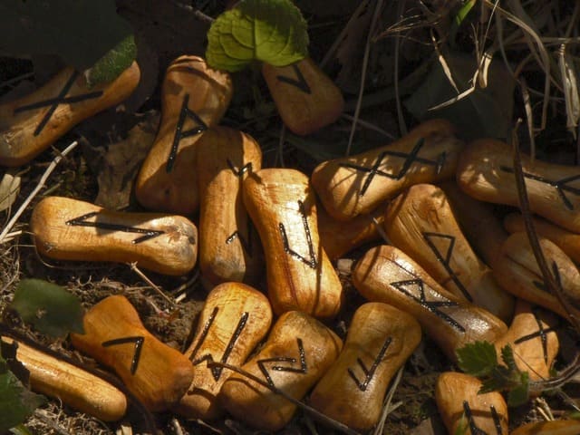 Foto de runas de madeira em cima de relva. em A imagem ilustra o artigo O que são Runas e o significado das runas do site Ori Mystyco.