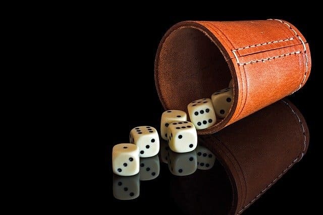 Foto de copo de couro caramelo deitado sobre a mesa com alguns dados saindo dele. Foto utilizada para ilustrar a Dominomancia online Leitura de Dominós Online Ori Mystyco